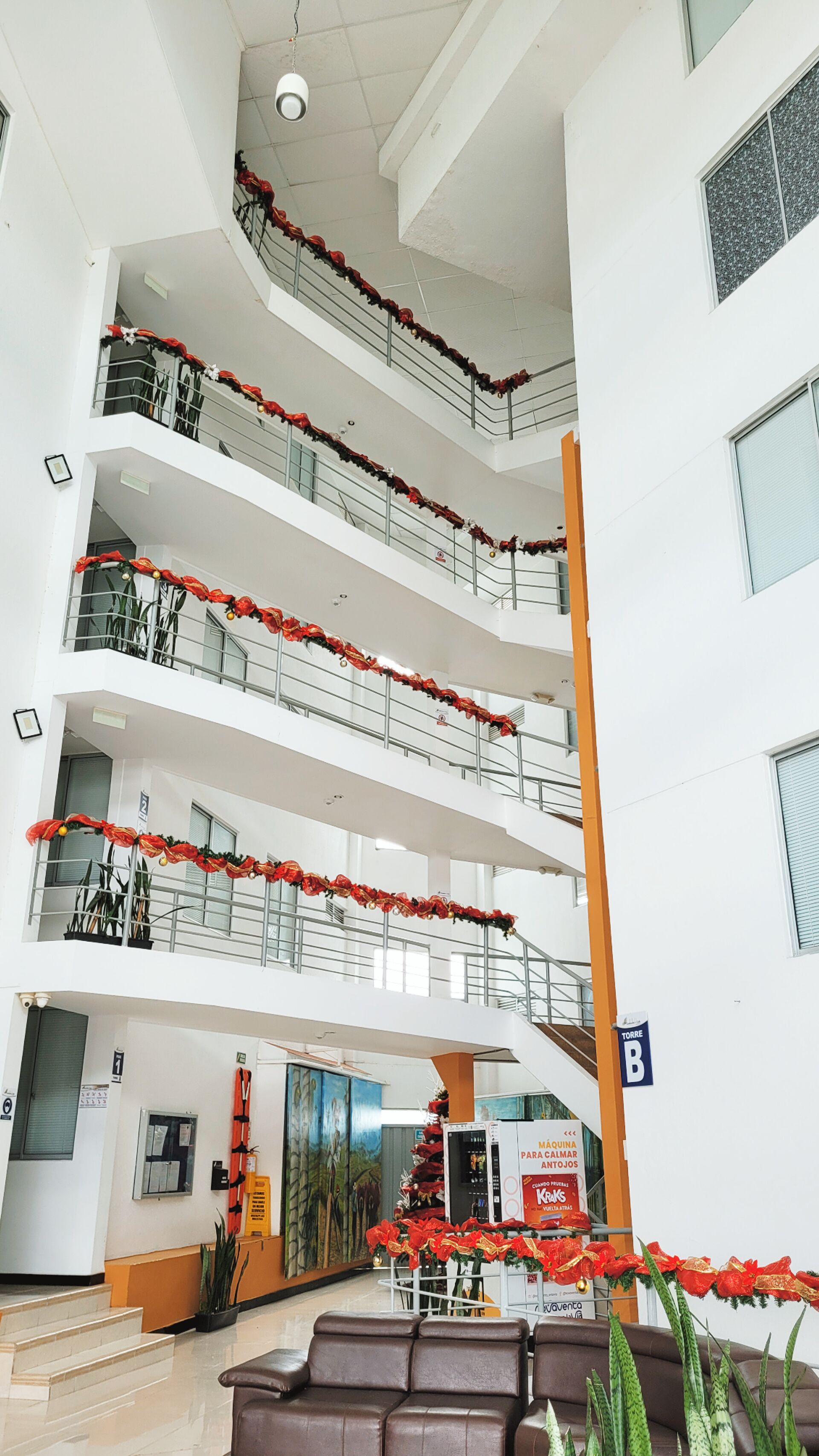 Un atrium à plusieurs niveaux, doté de balcons ornés de compositions florales rouges.