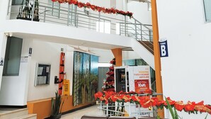 Un atrio a più livelli con balconi decorati da composizioni floreali rosse.