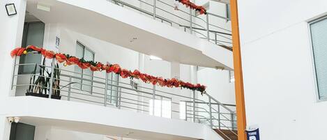 A multi-level atrium with balconies decorated with red floral arrangements.
