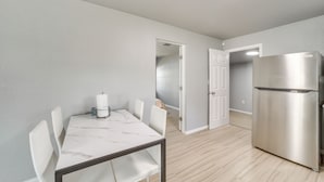 A modern kitchen with a stainless steel refrigerator, a marble-top dining table with chairs, and light wooden flooring. - Convenient Tulsa Home - 2 Mi to Downtown! (Tulsa)