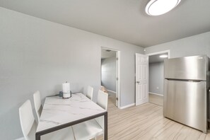 A modern kitchen with a stainless steel refrigerator, a marble-top dining table with chairs, and light wooden flooring. - Convenient Tulsa Home - 2 Mi to Downtown! (Tulsa)