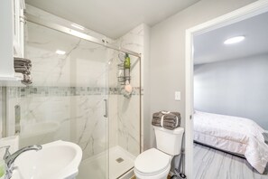 Un baño con ducha de vidrio, lavamanos blanco y retrete.