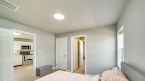 A bedroom with a bed, bedside table, and a view of the kitchen. - Convenient Tulsa Home - 2 Mi to Downtown! (Tulsa)
