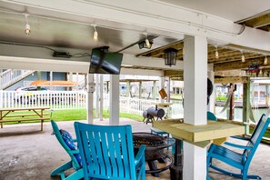 Ein Außenbereich mit einer Terrasse, blauen Stühlen, einem Holztisch und einem Grill.
