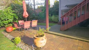 A patio with outdoor furniture, a potted plant, and a staircase leading to a house. - Private Edmonds Studio Apartment (Edmonds)