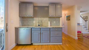A kitchen with grey cabinets, a dishwasher, and a tiled backsplash. - Nature Lover's Pondside Getaway (Mashpee)