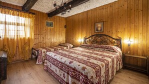 Une pièce aux murs lambrissés, avec un grand lit, deux tables de chevet et un lustre.