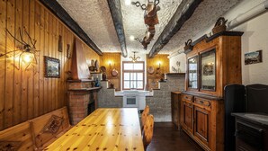 Une cuisine rustique avec des murs en bois, une cheminée en pierre et une table à manger en bois.