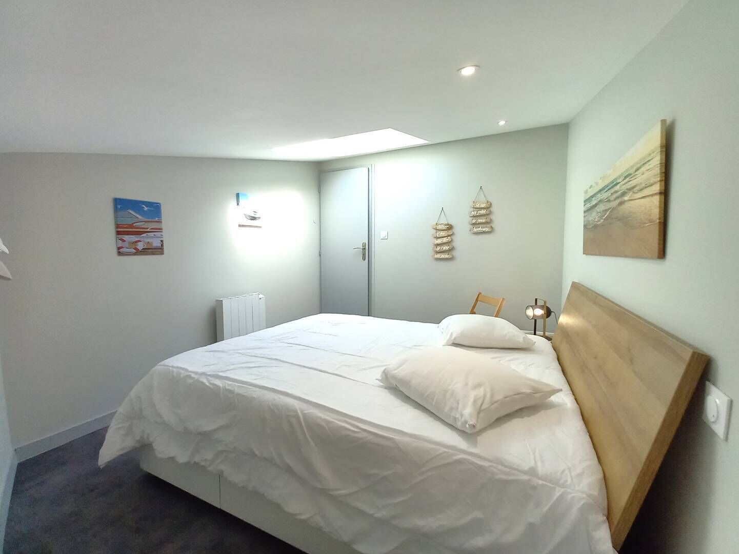 Quarto com uma cama grande, cabeceira de madeira, radiador e luminária no teto.
