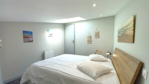 Ein Schlafzimmer mit einem großen Bett, einem Holz-Kopfteil, einem Heizkörper und einer Deckenleuchte.