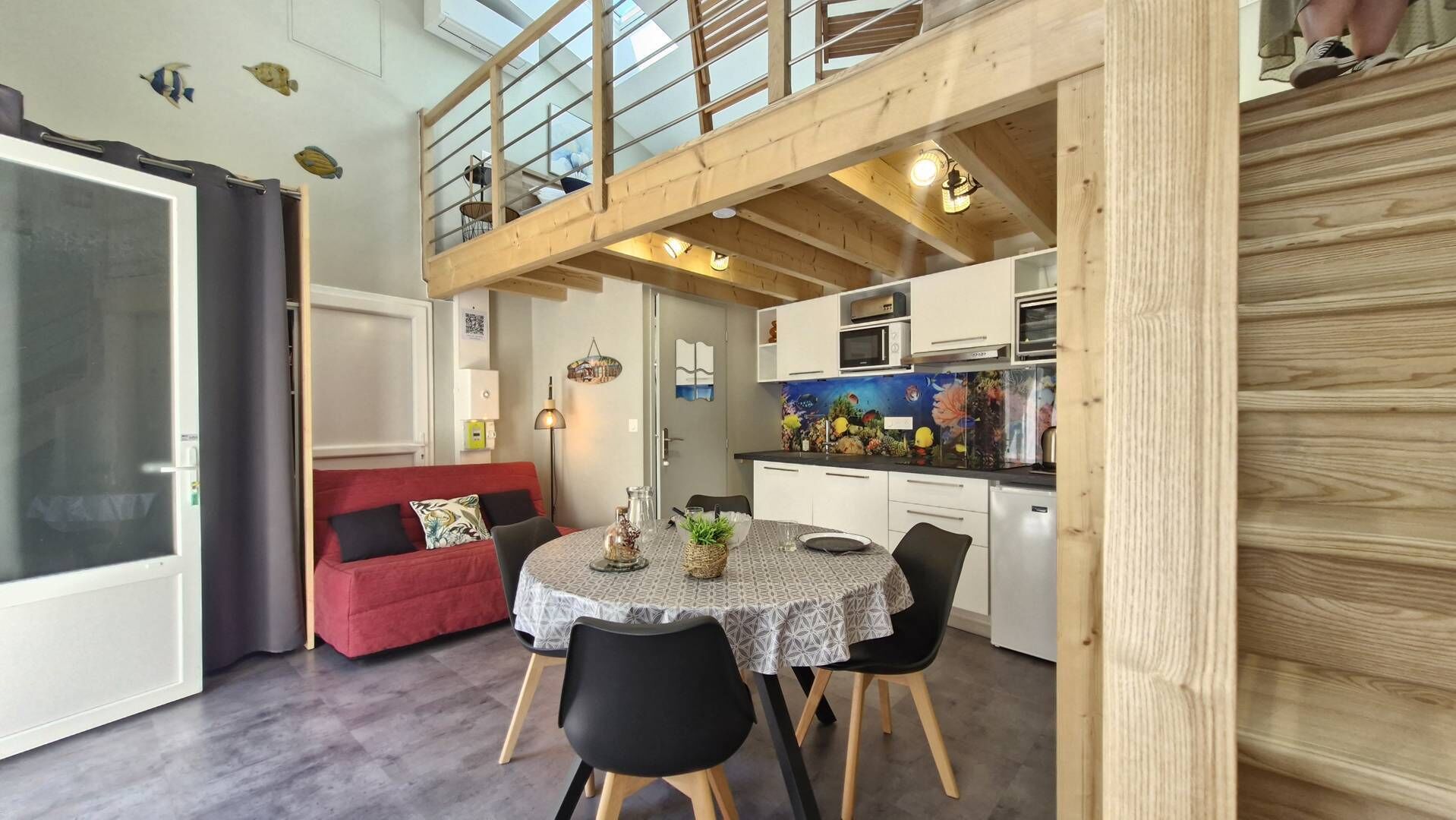 A compact living space with a dining area, a kitchenette, and a red sofa.