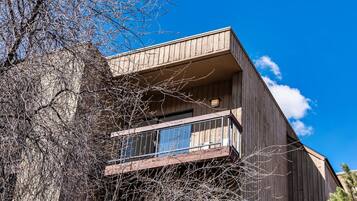 A modern two-story building with a wooden exterior and a balcony with a metal railing.