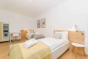 Relax in a spacious room with a large bed, bedside table, and desk, perfect for work or rest.