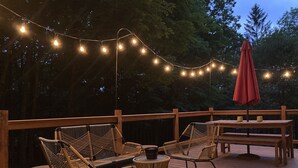 Une terrasse extérieure avec des meubles en osier, une table et des guirlandes lumineuses.