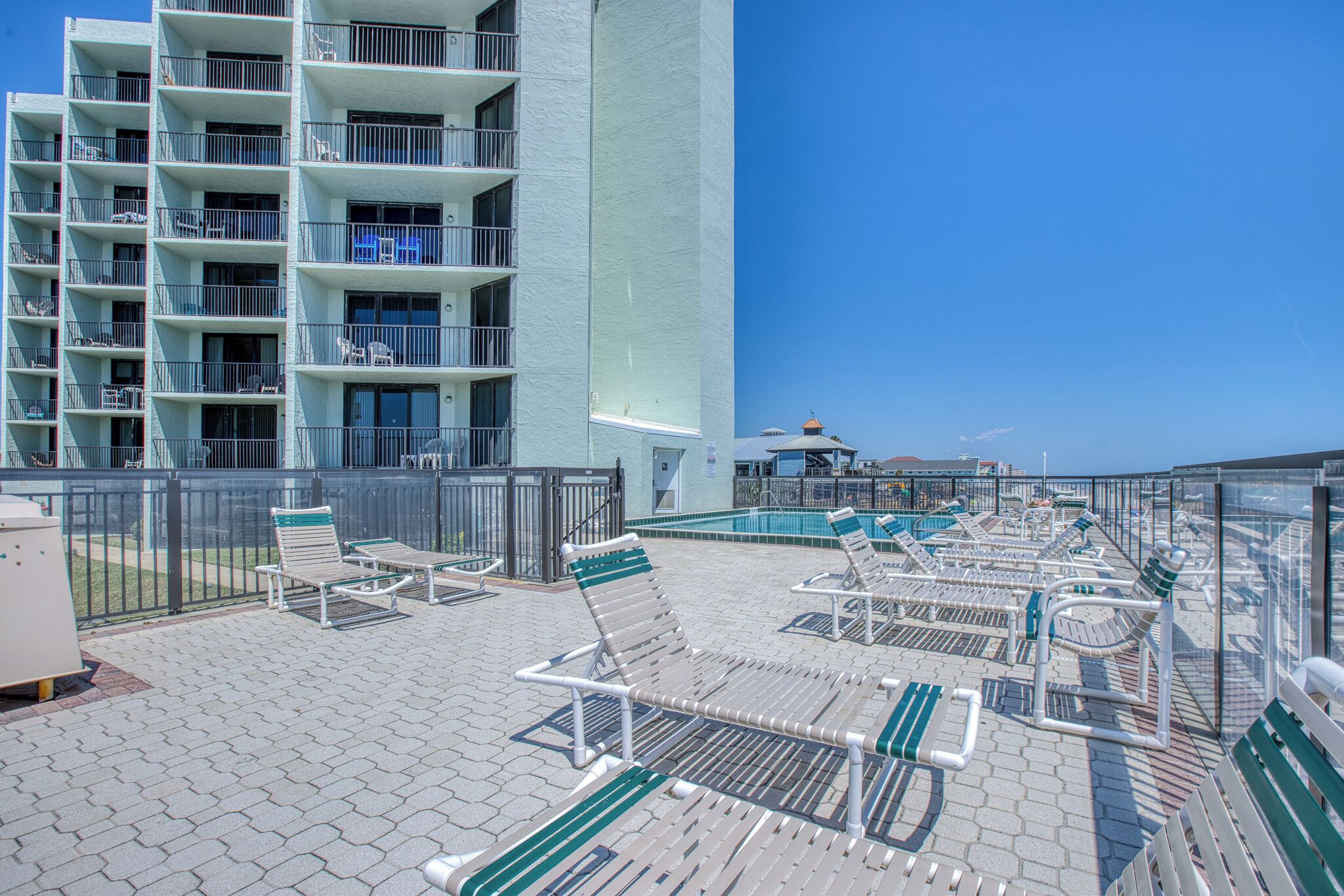 A rooftop pool area with lounge chairs and a view of a high-rise building.