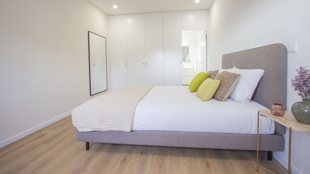 Une chambre à coucher moderne avec un lit, une table de chevet et un miroir.