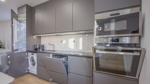 Une cuisine moderne dotée d’appareils électroménagers intégrés, de meubles de couleur grise et d’un lave-vaisselle.