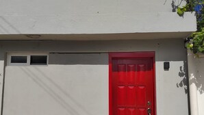 A red door with a small window above it, set in a plain wall. - 10 Ave Suite (Cozumel)