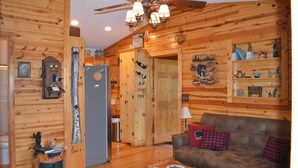 A wooden interior with a brown sofa, a coffee table, and a ceiling fan. - Quaint cabin with a creek in front that will lull you to sleep and pets allowed (Hiawassee)