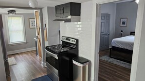 A compact kitchen with a stove, a trash bin, and a small cabinet. - Cozy Cottage @ Trevecca (Nashville)