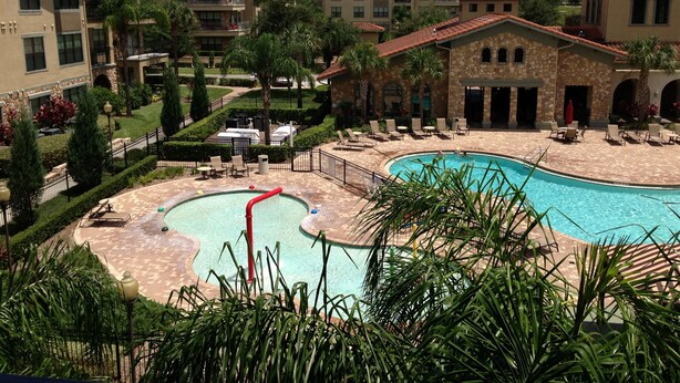 Um resort com piscina central, vários edifícios com varandas e uma área de jardim bem cuidada.