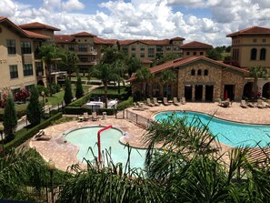 A resort with a central swimming pool, multiple buildings with balconies, and a well-maintained garden area. - Pool View with kitchen, washer dryer and minutes to Disney (Davenport)