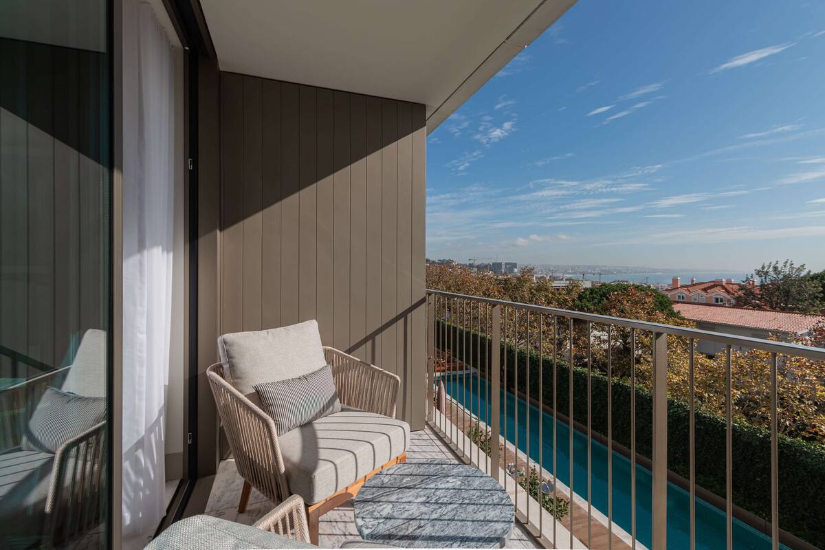 Un balcón con vista a una piscina y edificios lejanos.