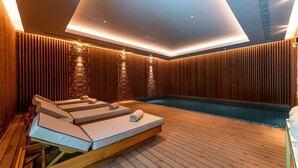 A modern spa room with wooden paneling, a pool, and lounge chairs. - Legacy Hotel Cascais, Curio Collection By Hilton (Cascais)