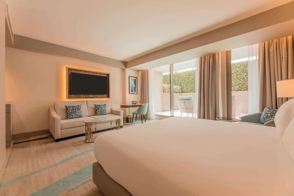 Una habitación de hotel con una cama grande, un sofá, un escritorio y un televisor.