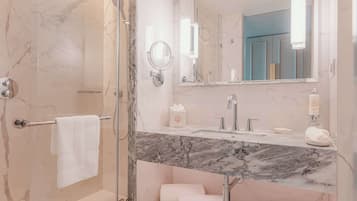 A modern bathroom with a marble vanity, a glass shower enclosure, and a large mirror.