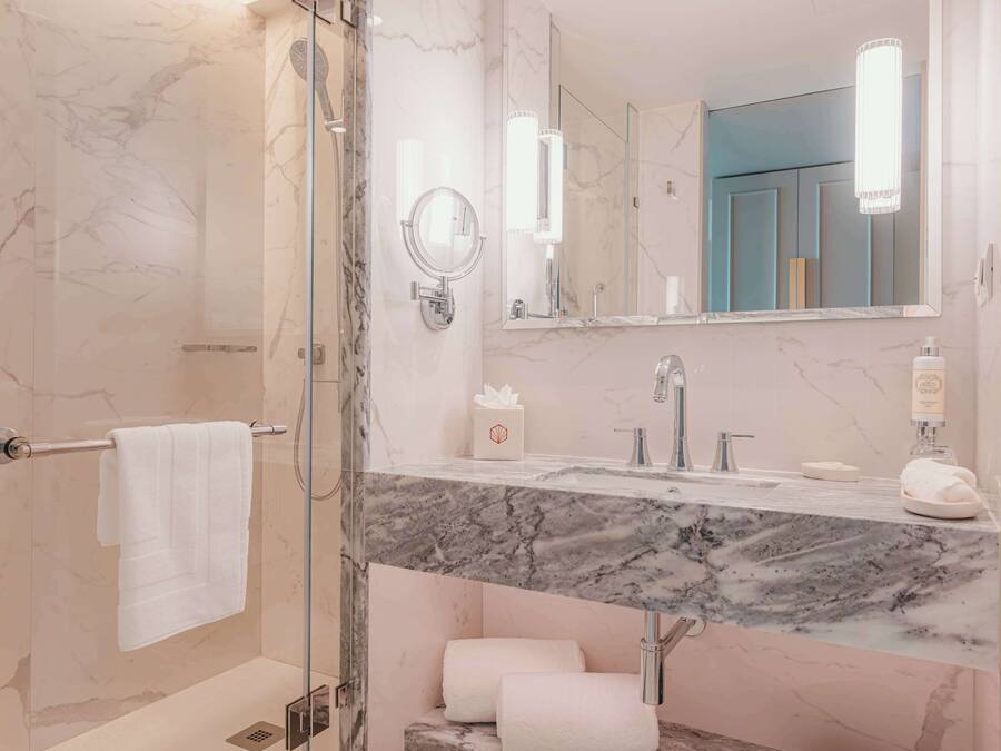 A modern bathroom with a marble vanity, a glass shower enclosure, and a large mirror.