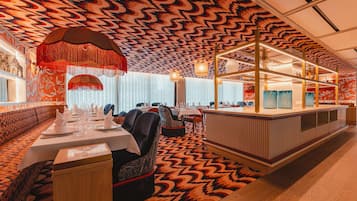 A restaurant with a patterned ceiling, wooden paneling, and a central bar area.