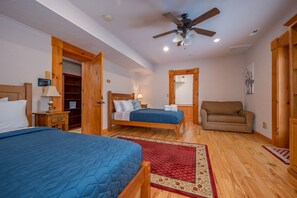 Ein Schlafzimmer mit zwei Betten, einem Deckenventilator, Holzmöbeln und einem roten Teppich.