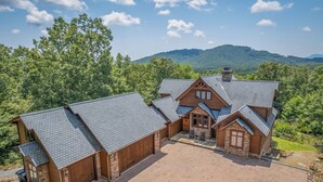 A large log cabin with multiple attached structures, a paved driveway, and a scenic forested backdrop. - Chateau Laurel in Lake Lure | Private 5,000 Sq Ft Cabin in Blue Ridge Mountains! (Lake Lure)