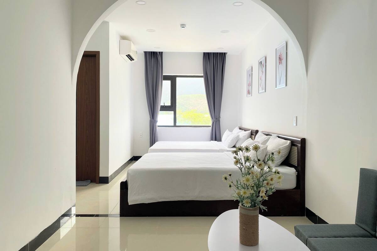Ein modernes Hotelzimmer mit einem großen Bett, einem kleinen Tisch und Blick ins Freie.
