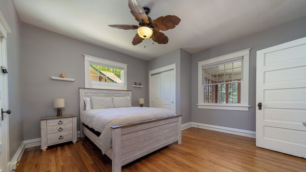A bedroom with a wooden bed, a ceiling fan, and two windows. - Best Location downtown GJ - Beautifully updated 2 Bedroom! (Grand Junction)