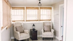A room with two armchairs, a small table, and a lantern. There are three windows with wooden shutters. - Best Location downtown GJ - Beautifully updated 2 Bedroom! (Grand Junction)