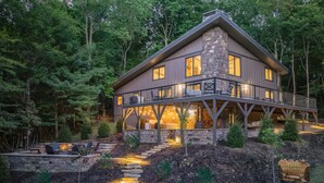 A two-story house with a stone facade and a balcony, surrounded by a forested landscape. - *Luxury* Home, Ski in/out, Hot Tub, Firepit, Games & More! (Beech Mountain)