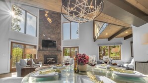 A modern dining area with a glass table, white plates, and wine glasses. - *Luxury* Home, Ski in/out, Hot Tub, Firepit, Games & More! (Beech Mountain)