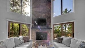 A modern living room with a stone fireplace, two grey sofas, and a coffee table. - *Luxury* Home, Ski in/out, Hot Tub, Firepit, Games & More! (Beech Mountain)