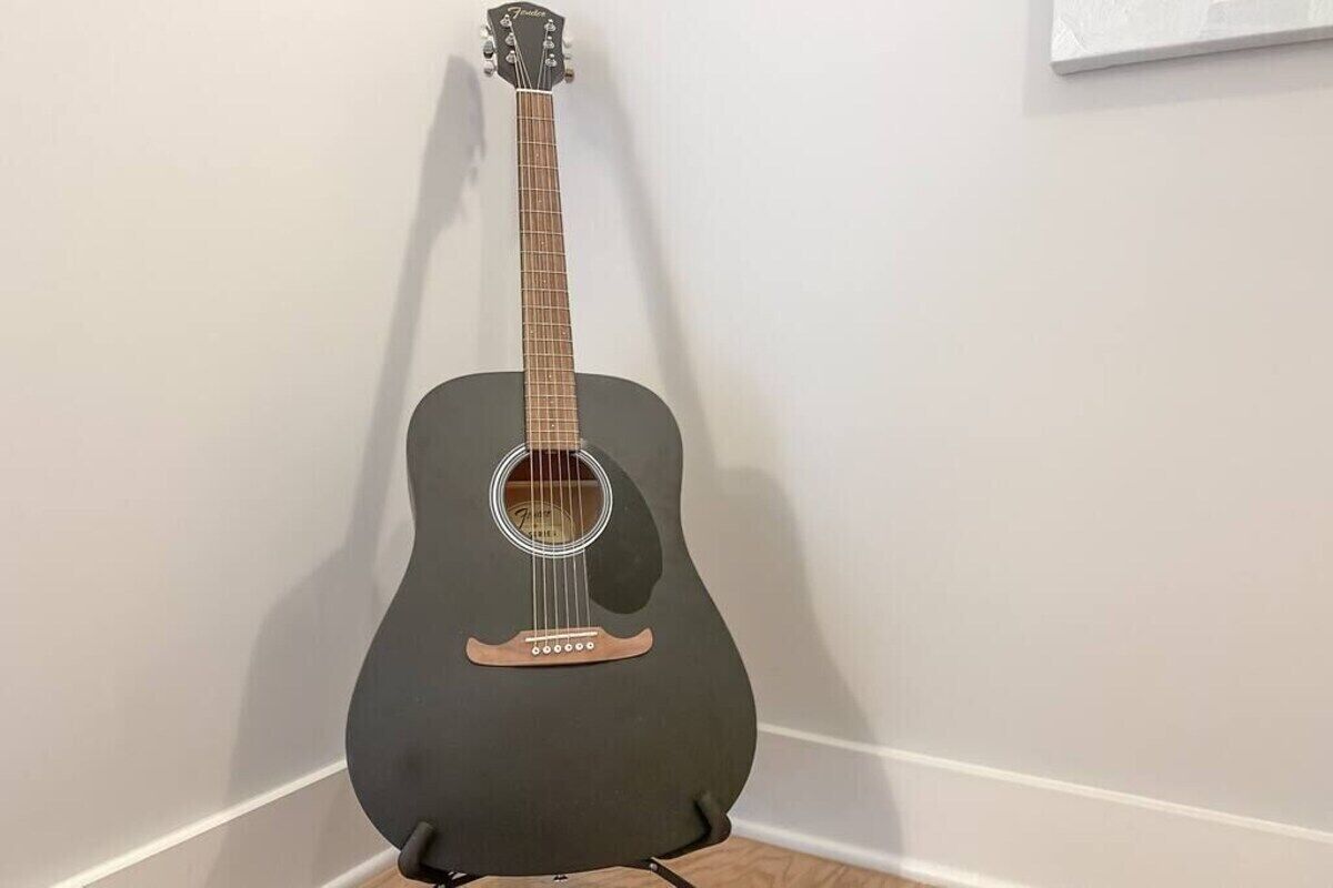 Una guitarra frente a una pared lisa.