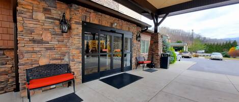 A stone building with a glass door, outdoor seating, and a covered patio area.