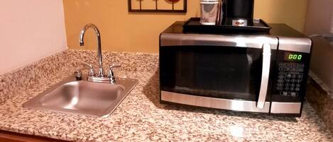 A compact kitchen with a stainless steel sink, a microwave, and a dishwasher.
