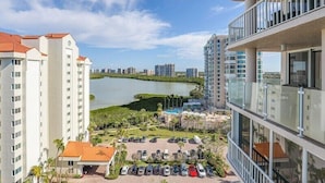 Un edificio alto con vistas a un lago y vegetación circundante.