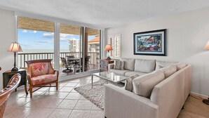 Un salón amplio con un gran ventanal, un sofá, una butaca y una mesa de comedor.