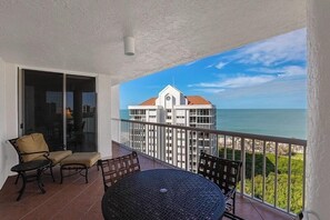 A balcony with a view of the ocean and a building in the background. - Enjoy this bright 10th flr beachfront condo-CL1003 (Naples)
