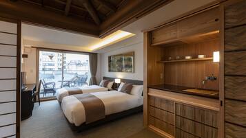 Ein Hotelzimmer mit zwei Betten, einem Schreibtisch, einem Sessel, einem großen Fenster und einem Holzkorpus mit Waschbecken.