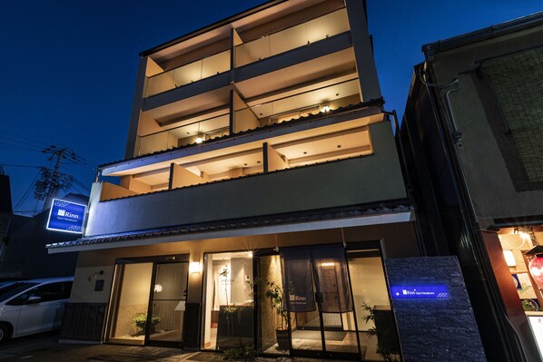 A multi-story hotel with a modern design, featuring balconies on the upper floors and a well-lit entrance. - Rinn Gion Hanatouro (Kyoto)