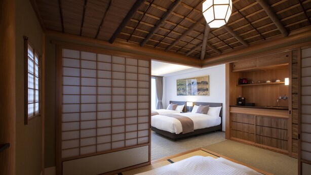 A traditional Japanese-style bedroom with tatami flooring, a large bed, a shoji screen, and a wooden ceiling. - Rinn Gion Hanatouro (Kyoto)