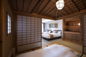 A traditional Japanese-style bedroom with tatami flooring, a large bed, a shoji screen, and a wooden ceiling. - Rinn Gion Hanatouro (Kyoto)